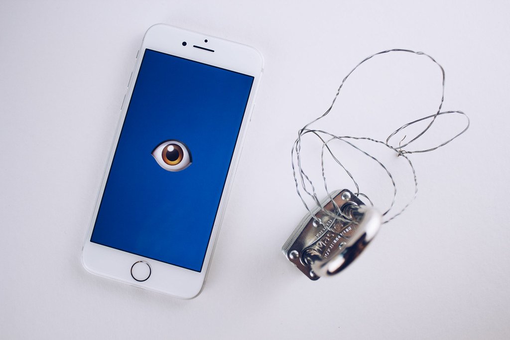 AI voice cloning scams concept image of a smartphone in shadowed hands